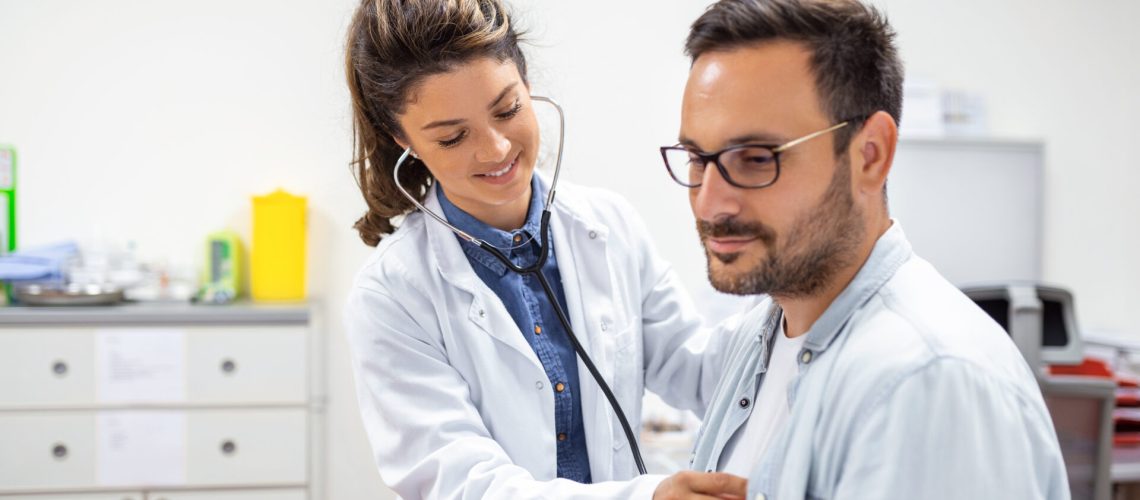 Young doctor is using a stethoscope listen to the heartbeat of the patient. Shot of a female doctor giving a male patient a check up